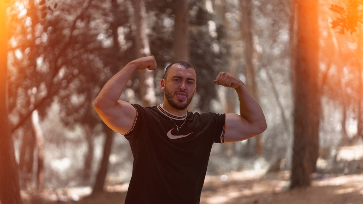 a man flexing his muscles in the woods